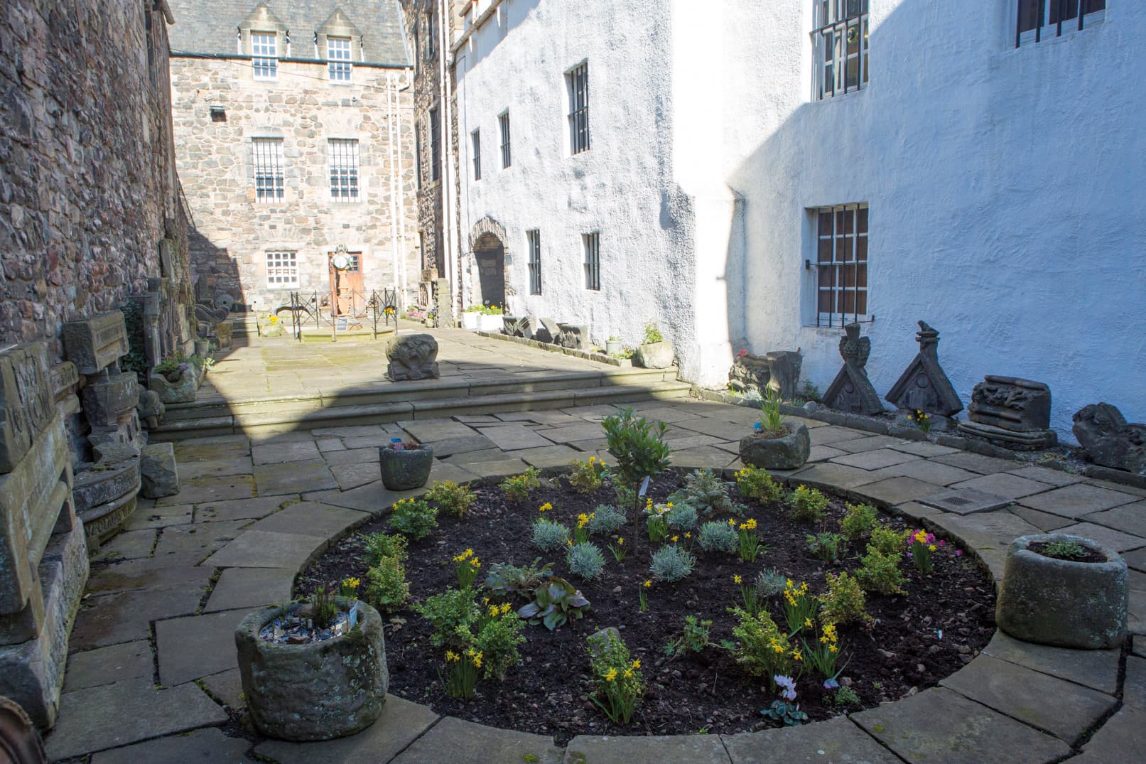 A charming courtyard with a flourishing flower garden, displaying an array of colorful flowers and rich foliage.