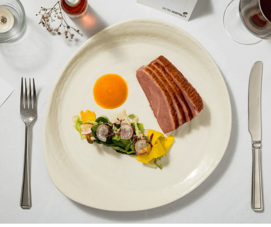 A plate featuring a portion of meat accompanied by a variety of colorful vegetables.