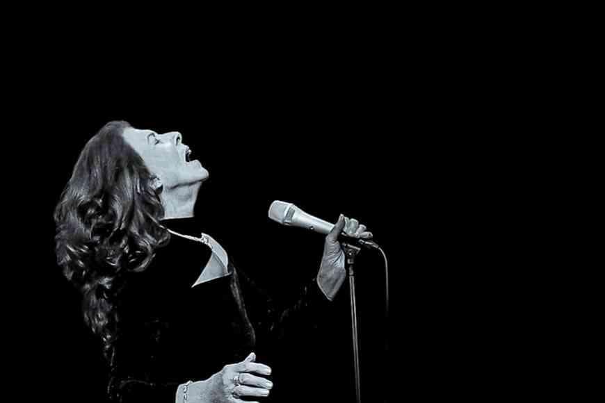A black and white photo Elkie Brooks singing into a microphone