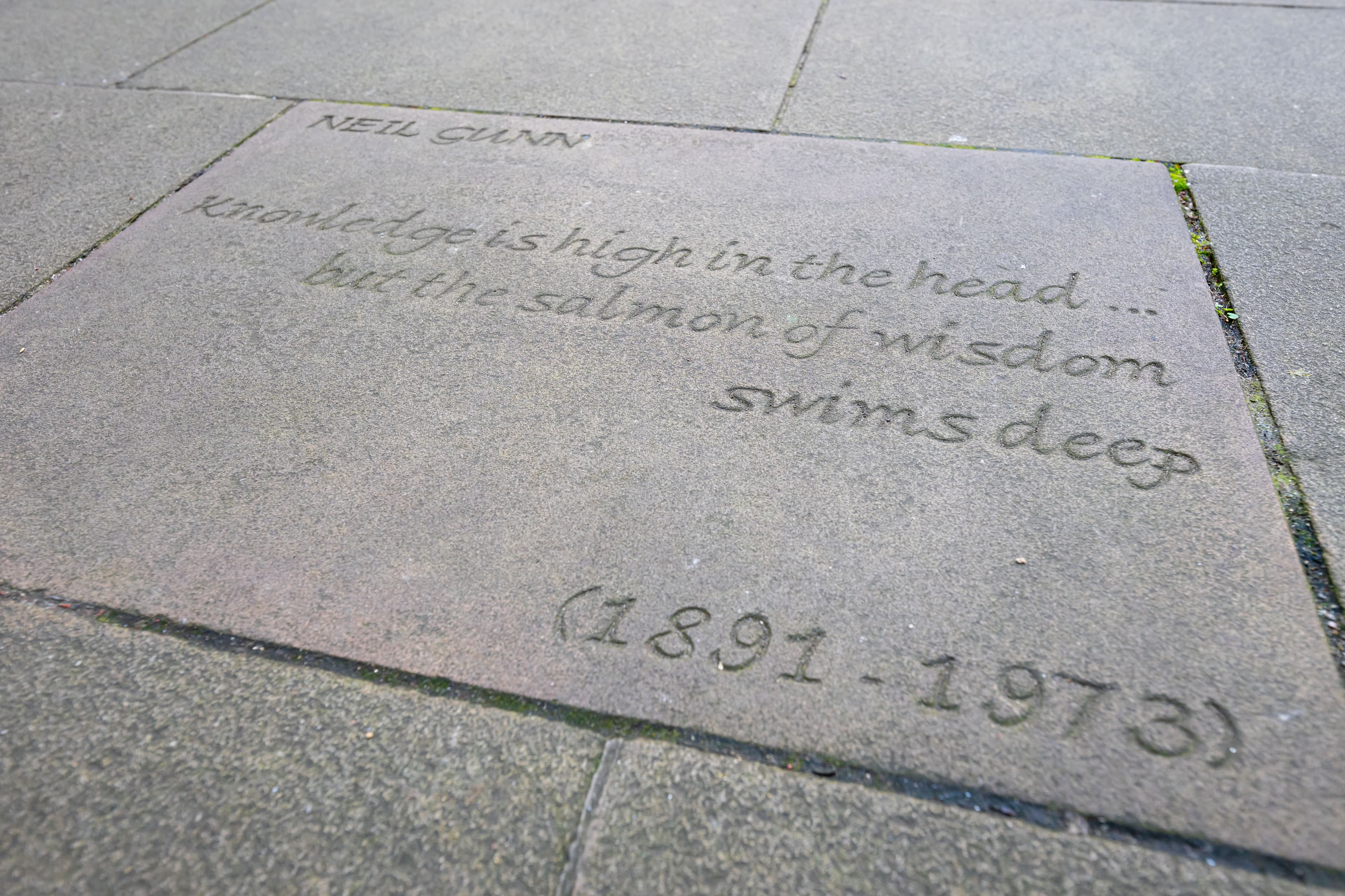 Grey courtyard slabs with words engraved on them.