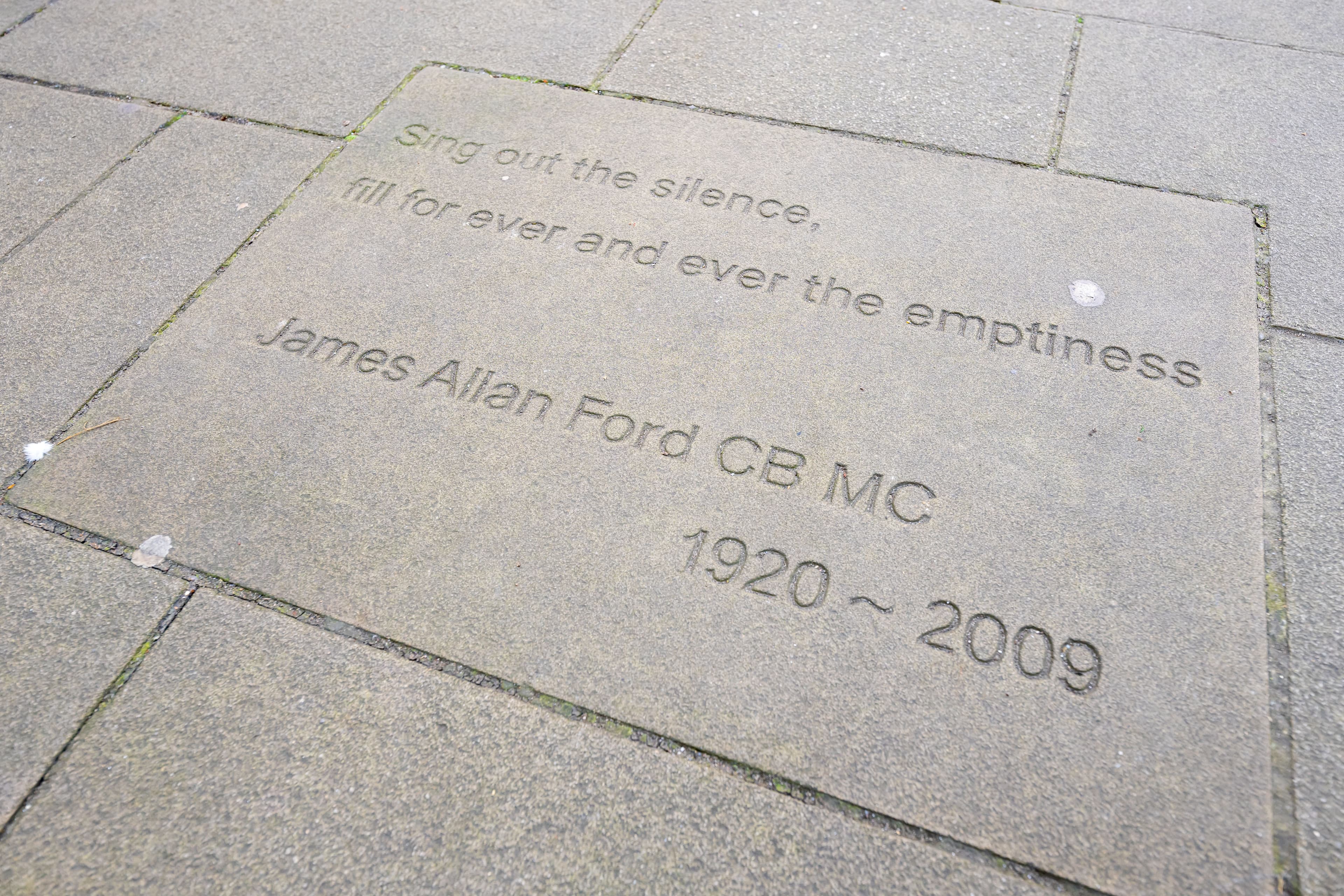 Grey courtyard slabs with words engraved on them.