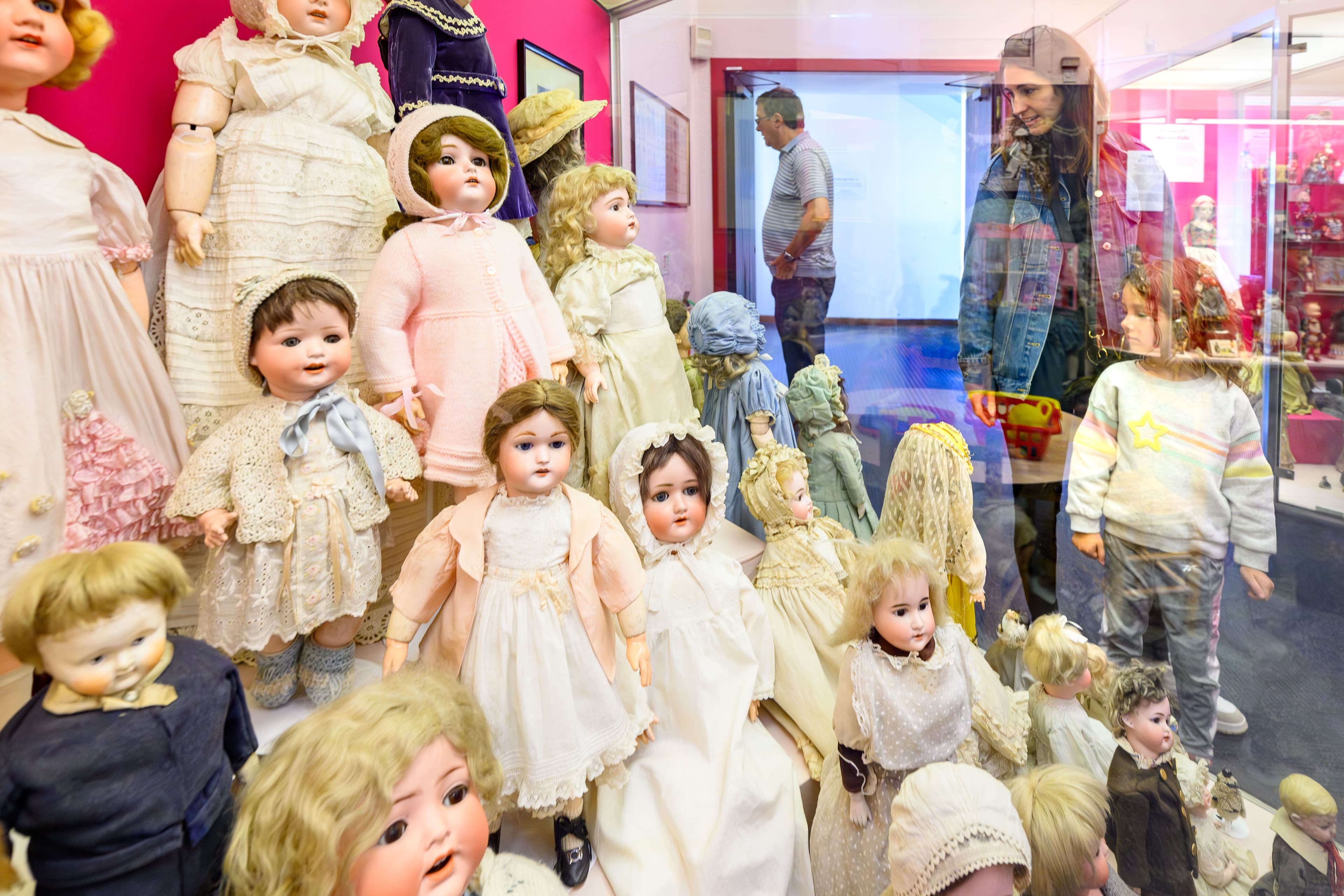 A room filled with various dolls displayed on shelves and tables, showcasing diverse styles and sizes.