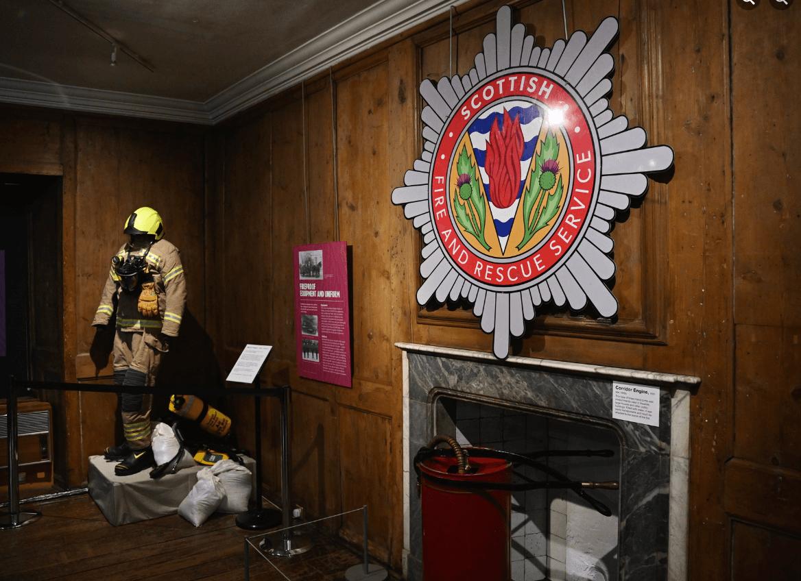 Museum exhibition space called the Huntly Room. Featuring wooden panelled walls and a fireplace.