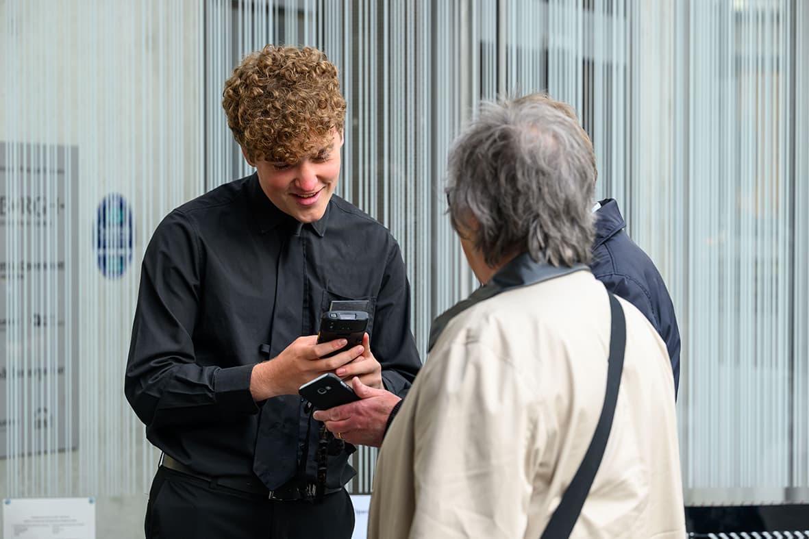 A staff member speaks to a woman, both appearing attentive and engaged in discussion about ticket entry to a concert