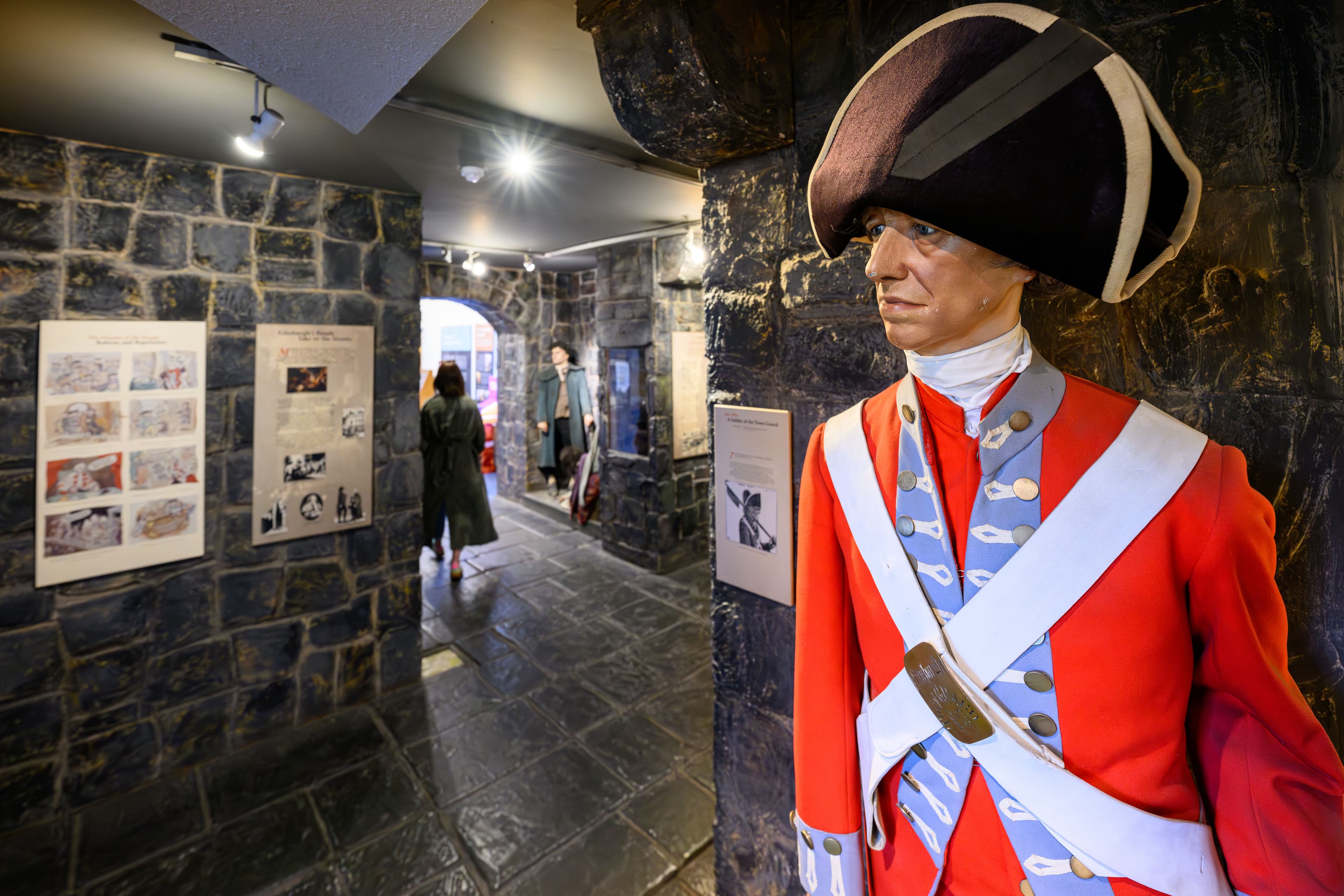 A mannequin statue of a man dressed in a vibrant red uniform, standing proudly with a serious expression.