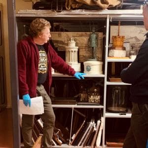 A volunteer stands next to a shelf packed with artefacts objects in the Museum Collections Centre in Edinburgh 