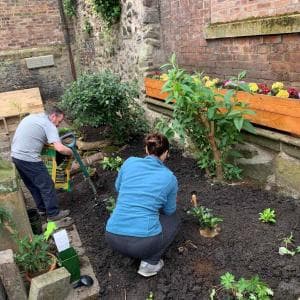 Two volunteers actively engaged in gardening in the courtyard at the Museum of Edinburgh