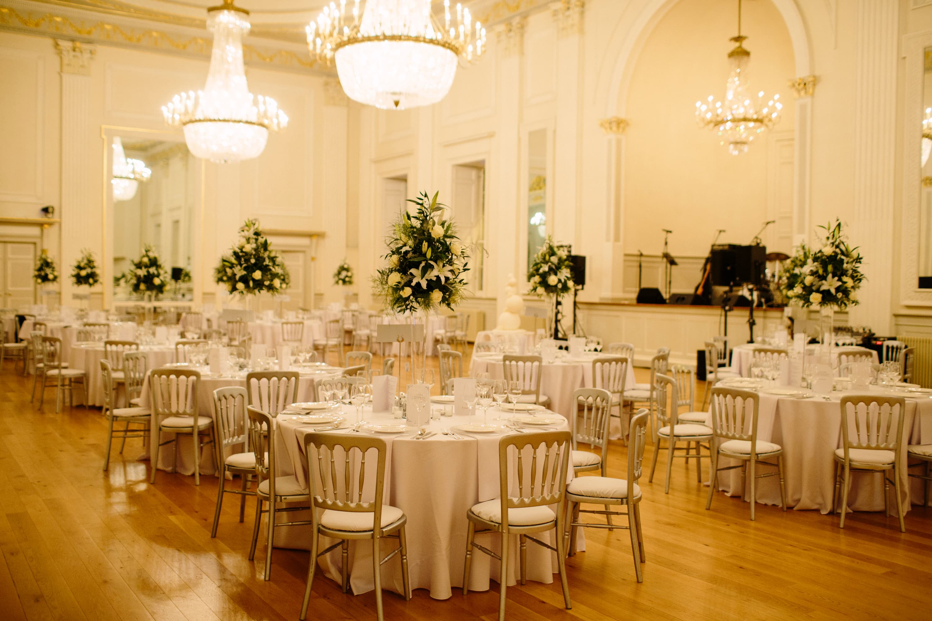 A spacious room arranged with tables and chairs, elegantly set up for a wedding or another type of celebration.