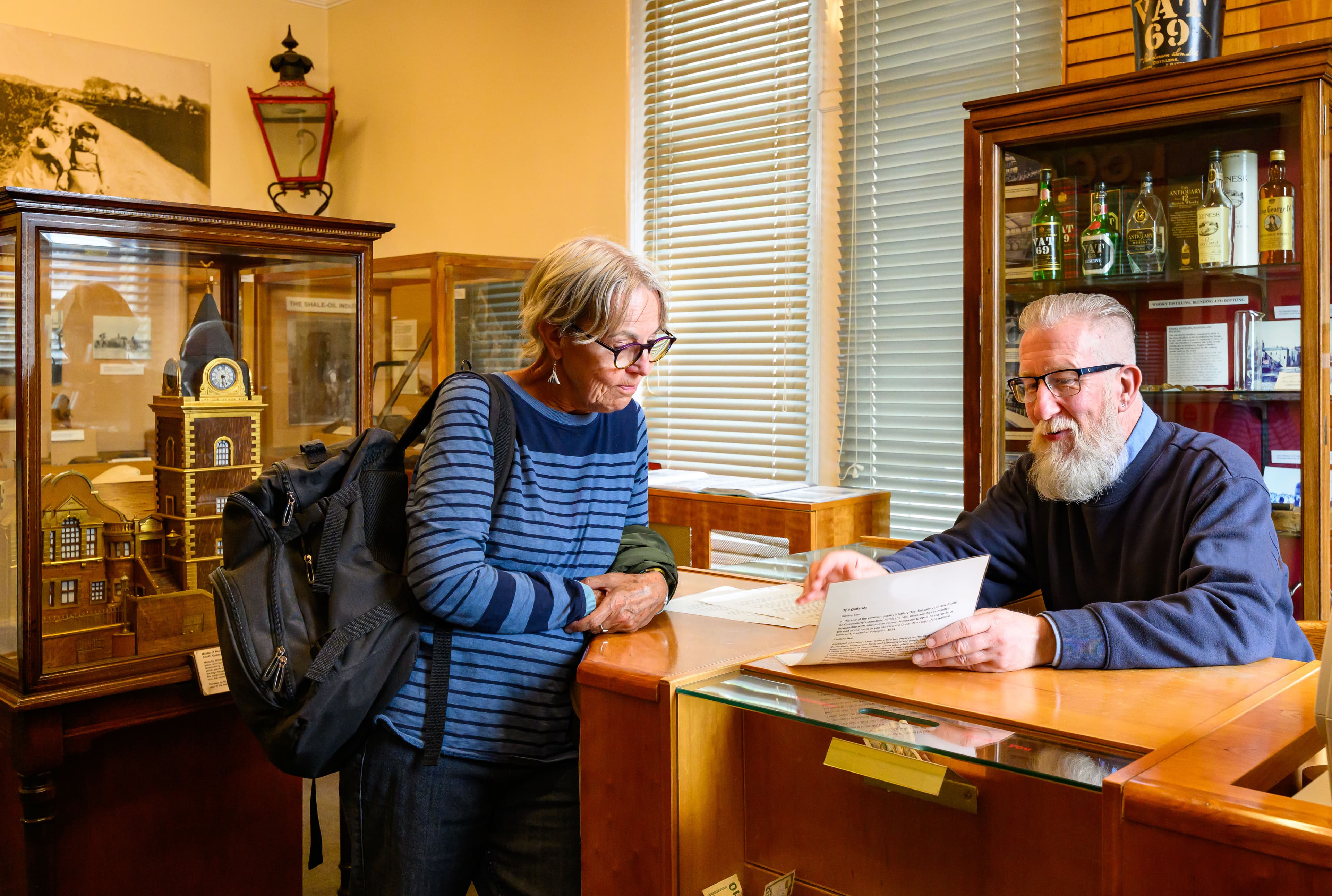 A man and woman stand together at the reception desk of the museum, engaged in conversation.