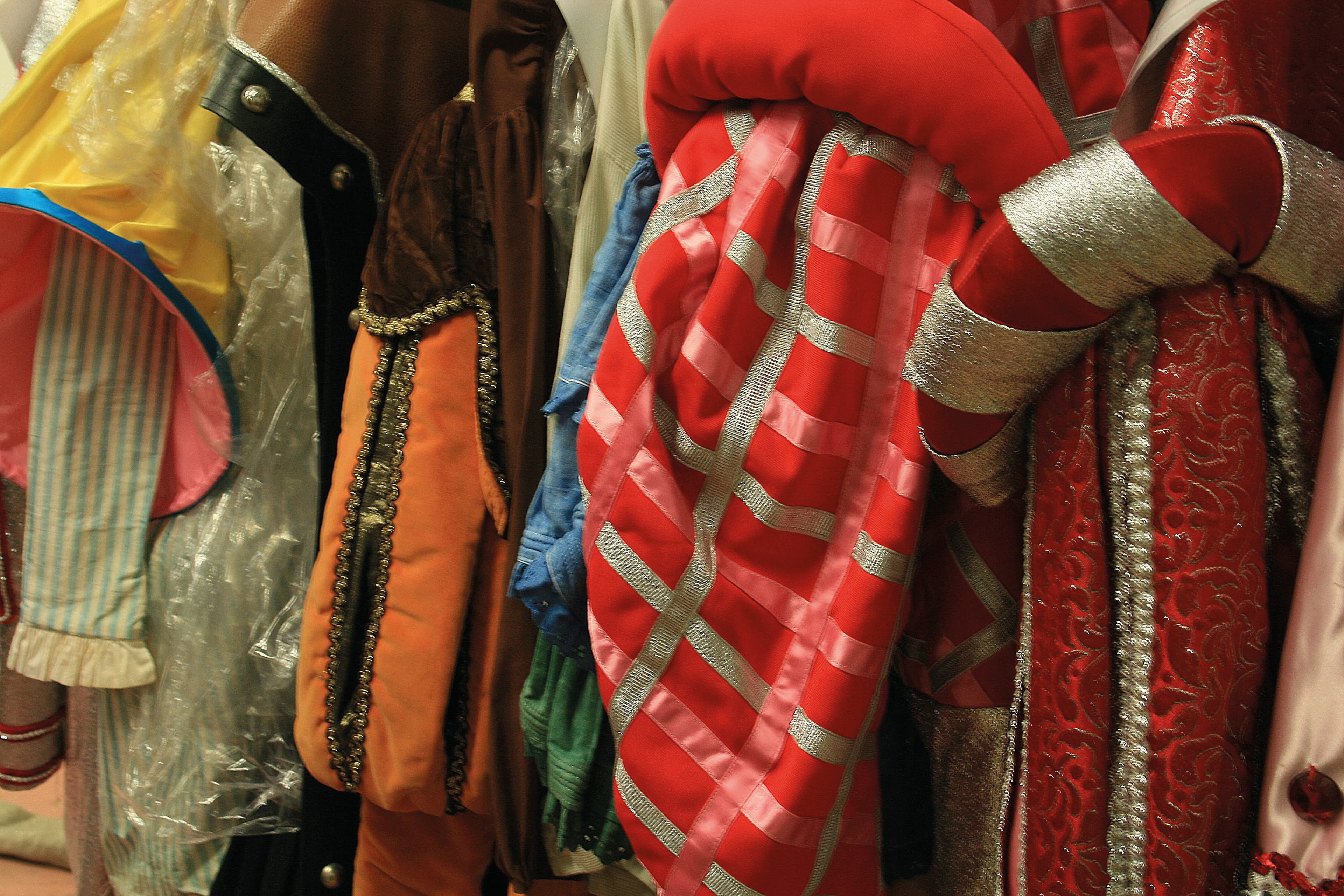 A rack displaying various colourful theatre clothing and costumes items, including shirts, dresses, and jackets, organized for easy browsing.