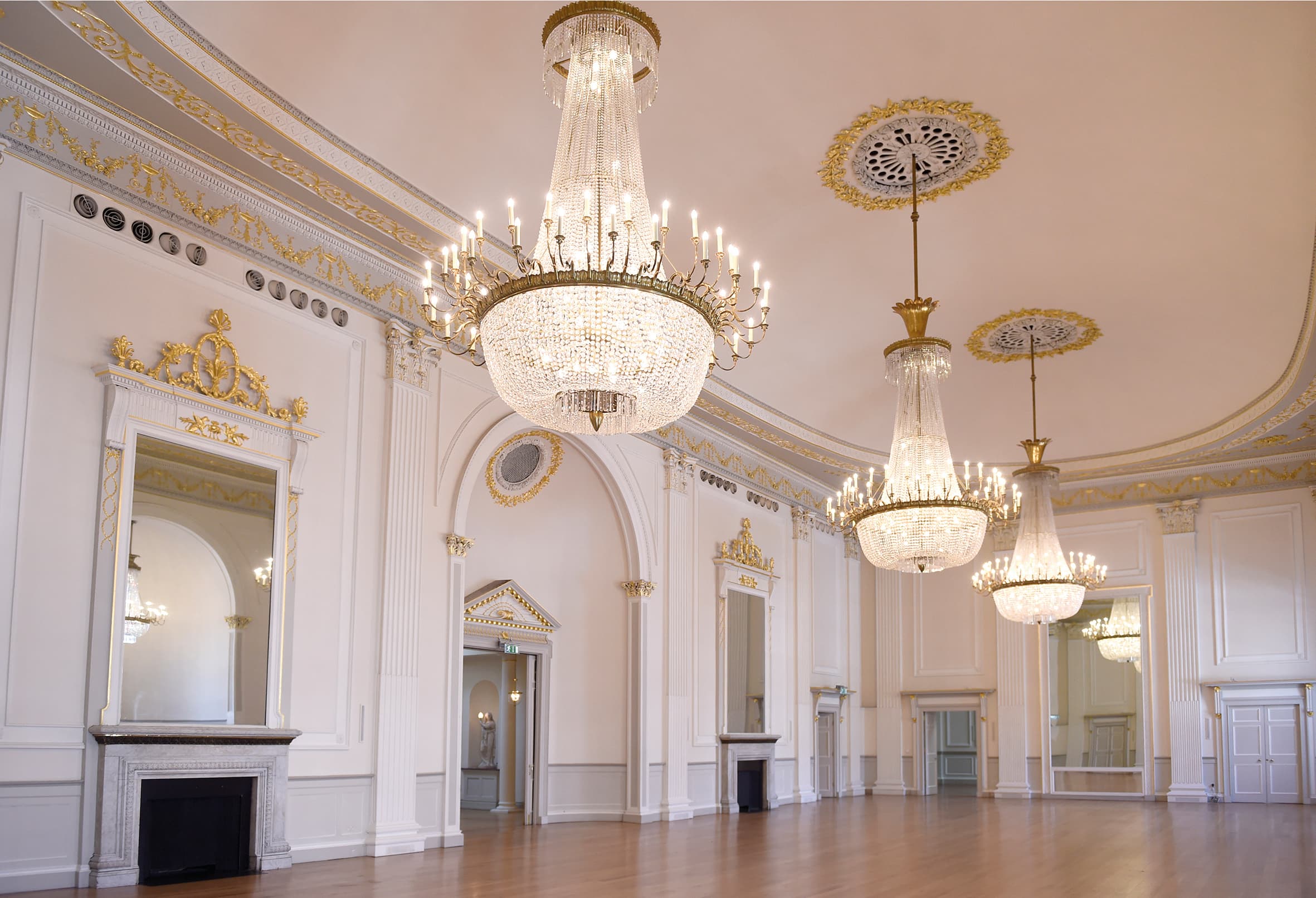 An expansive room featuring multiple chandeliers and mirrors, creating a bright and luxurious atmosphere.