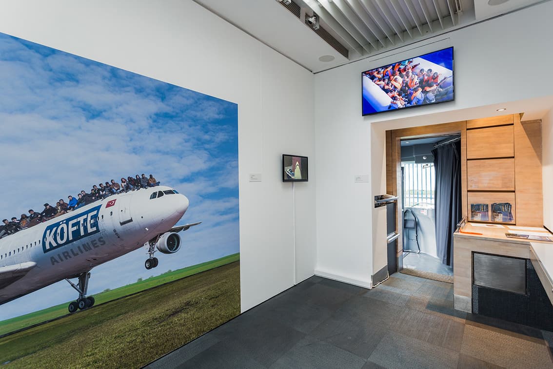 A broad white wall dominates the scene, with a large piece of artwork of a plane on it, creating an open and airy atmosphere inside the bus