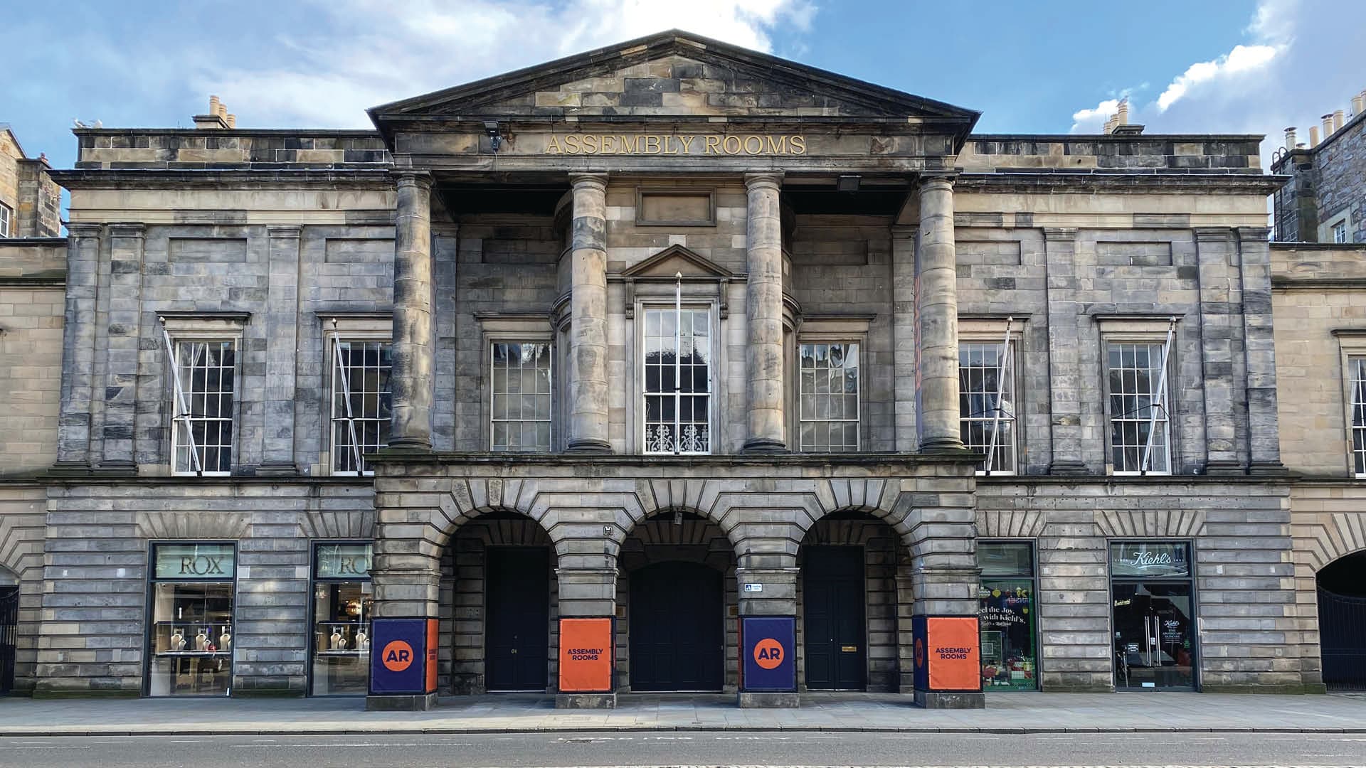 The grand entrance of the Assembly Rooms in Edinburgh, featuring ornate architecture and welcoming steps.