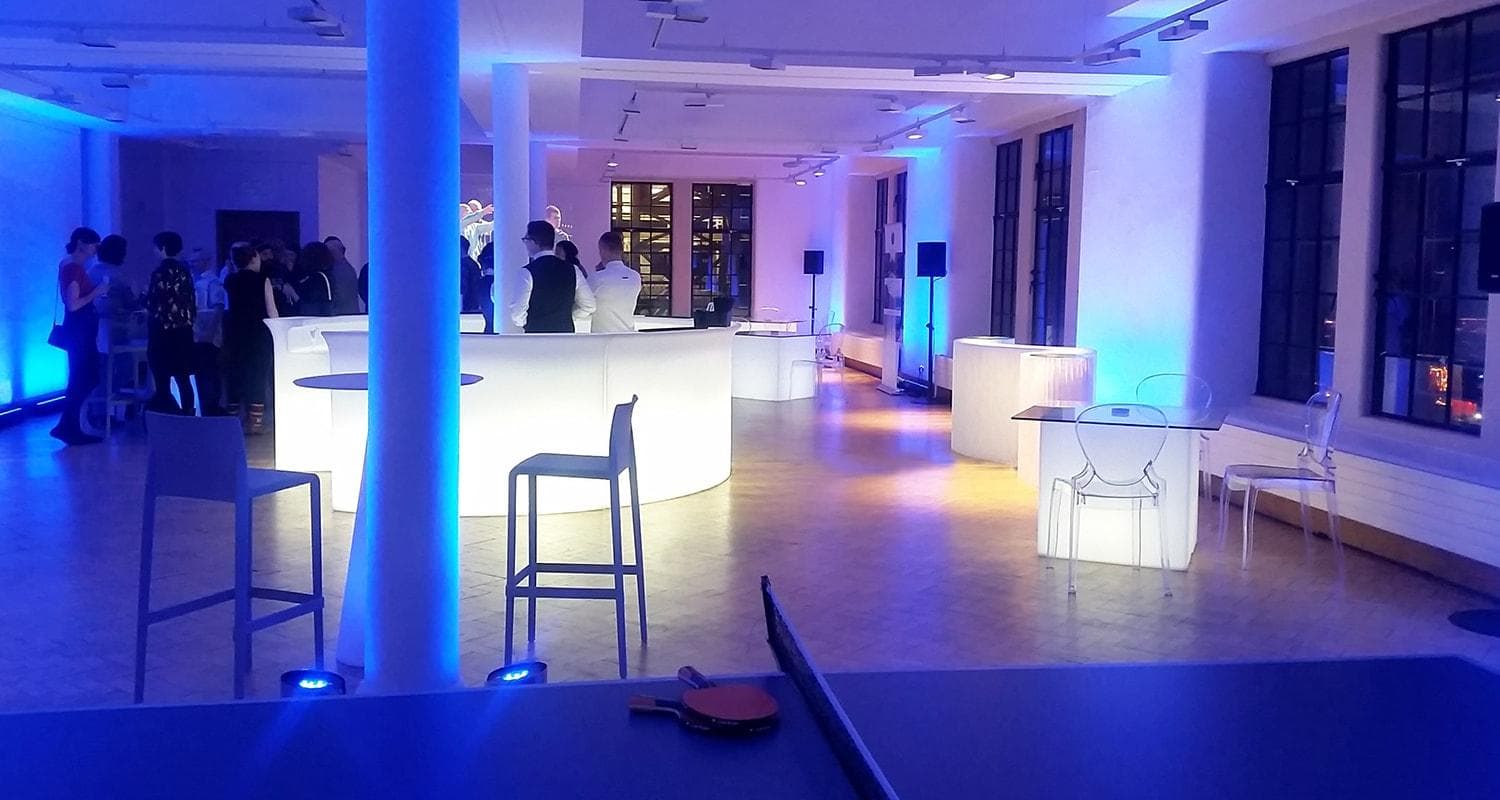 A spacious room on the fifth floor with tables and chairs bathed in blue light, suggesting a serene and modern setting.