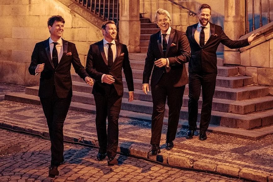 G4 in black suits walking down stairs in the street at night