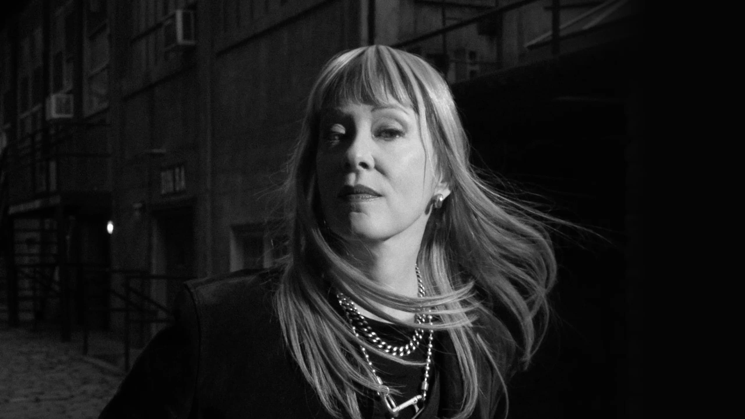 Black and white headshot of Suzanne Vega tossing her hair
