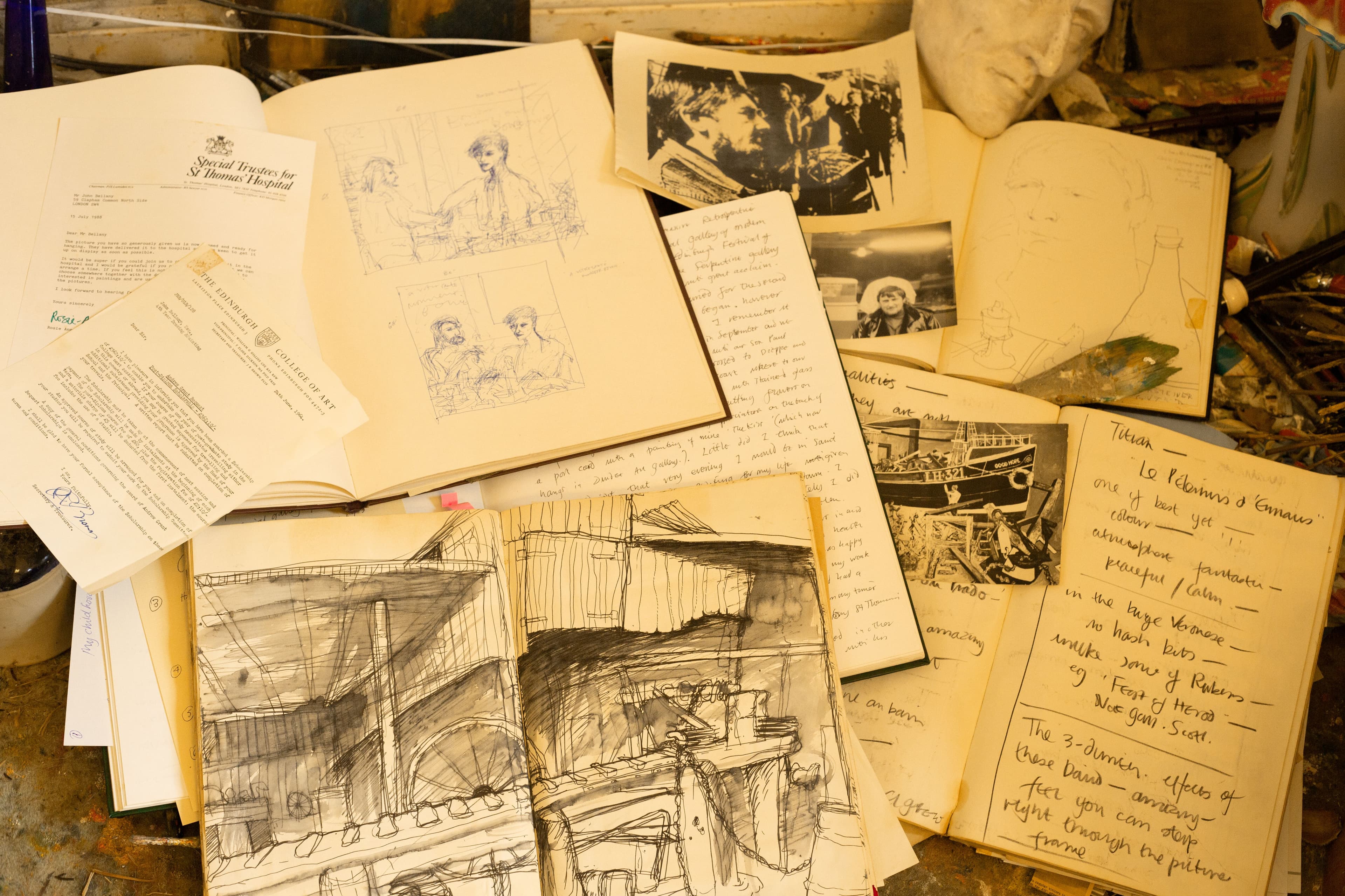 A cluttered table displaying a pile of letters and sketchbooks by the artist John Bellany.