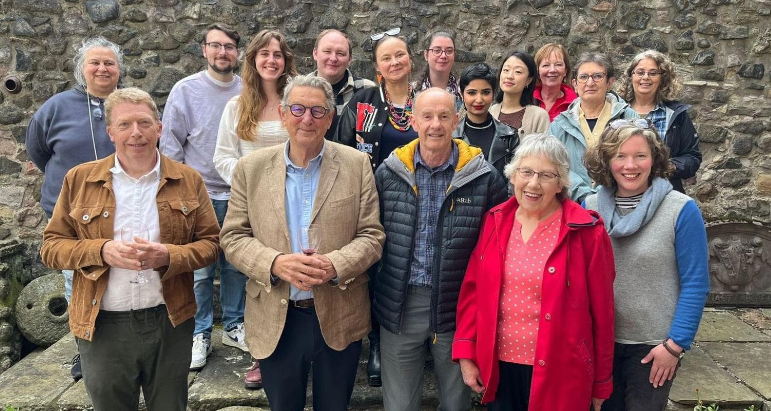 A group of people stand together smiling, in front of stone wall outside Edinburgh's Lauriston Castle