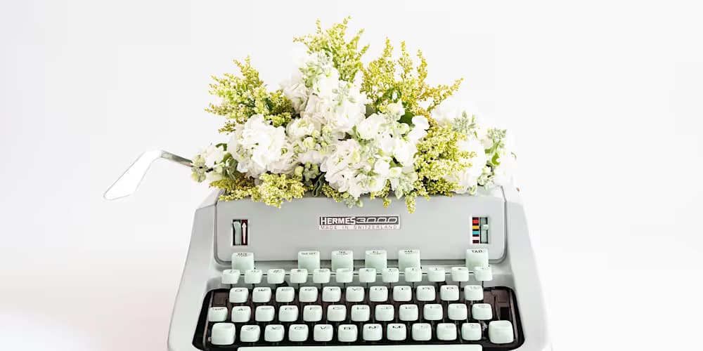White typwriter with white flowers and follage positioned instead of paper